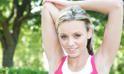 Picture of a woman, happy with her arms liposuction procedure she had at Top Plastic Surgeons in beautiful San Jose, Costa Rica.  The woman is facing the camera with arms outstretched with a backdrop of green trees.