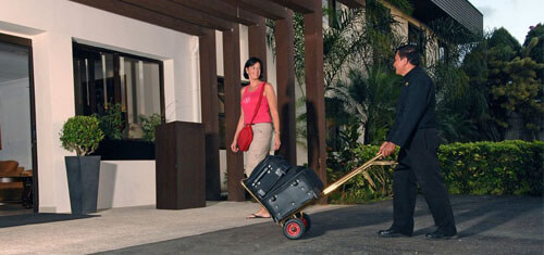 Picture of guests arriving at the beautiful Costa Rica Medical Center Inn in San Jose, Costa Rica.  The picture shows a guest arriving at the entrance and an employee bringing her luggage in a cart.