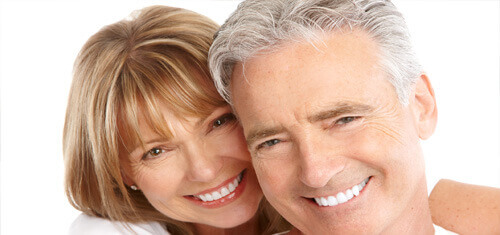 Close-up picture of a smiling couple looking directly into the camera showing their happiness with the plastic surgery they had in Costa Rica.  The woman has medium brown hair and the man has white hair.