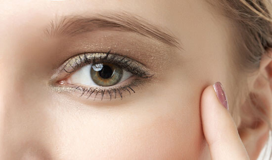 Picture of a woman, facing the camera and happy with her perfect eyelid lift procedure she had at Top Plastic Surgeons in beautiful San Jose, Costa Rica.  The woman has her hand to the side of her face and is pointing to the side of her eye with her index finger.