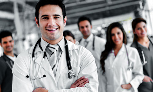 Picture of a group of doctors and assistants representing top plastic surgeons in San José, Costa Rica.  Five are standing in the back and one is standing in front of them with arms folded.